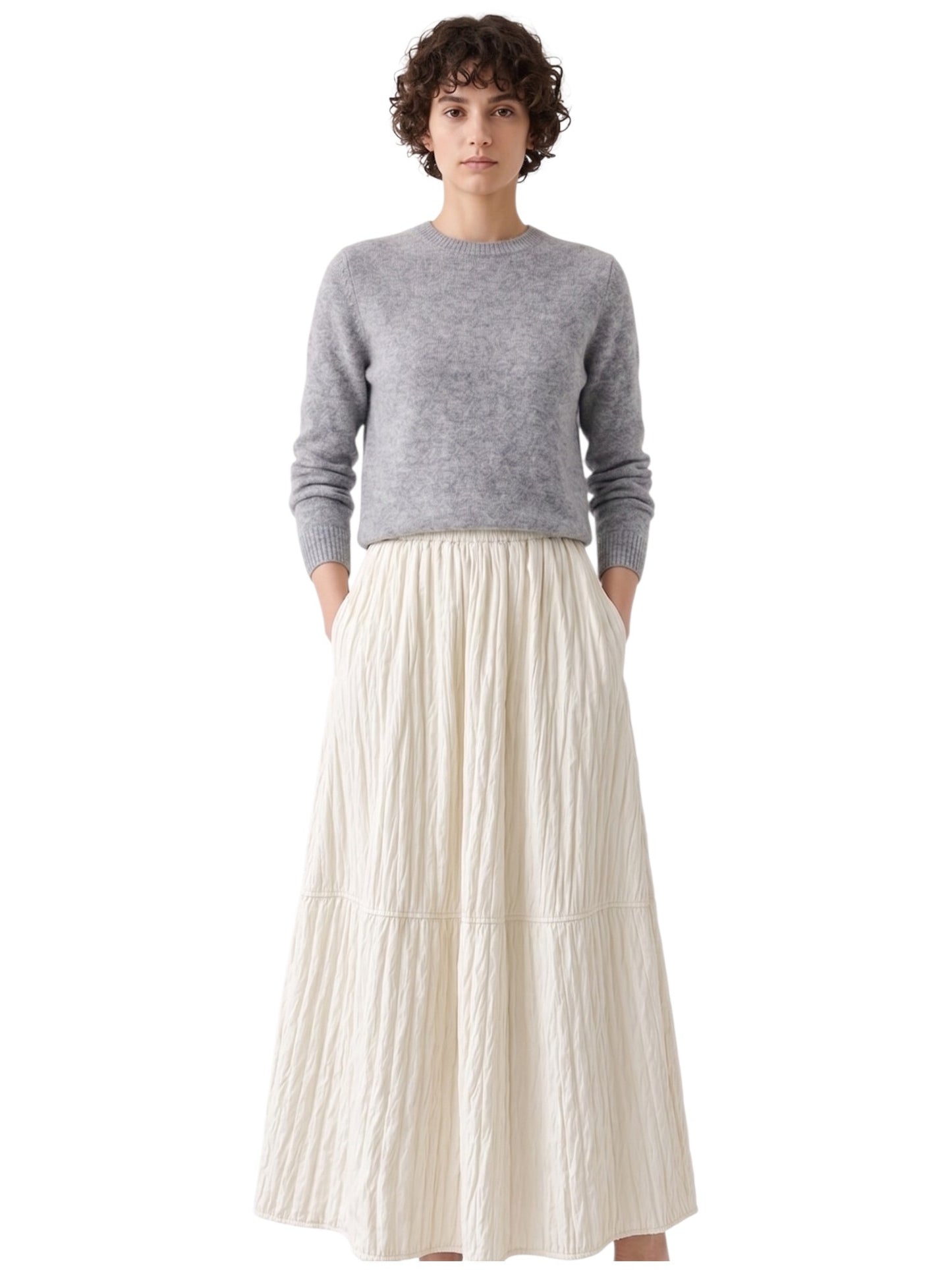 Cropped front view highlighting the hidden side pockets and gathered elastic waist on the ivory quilted long skirt.