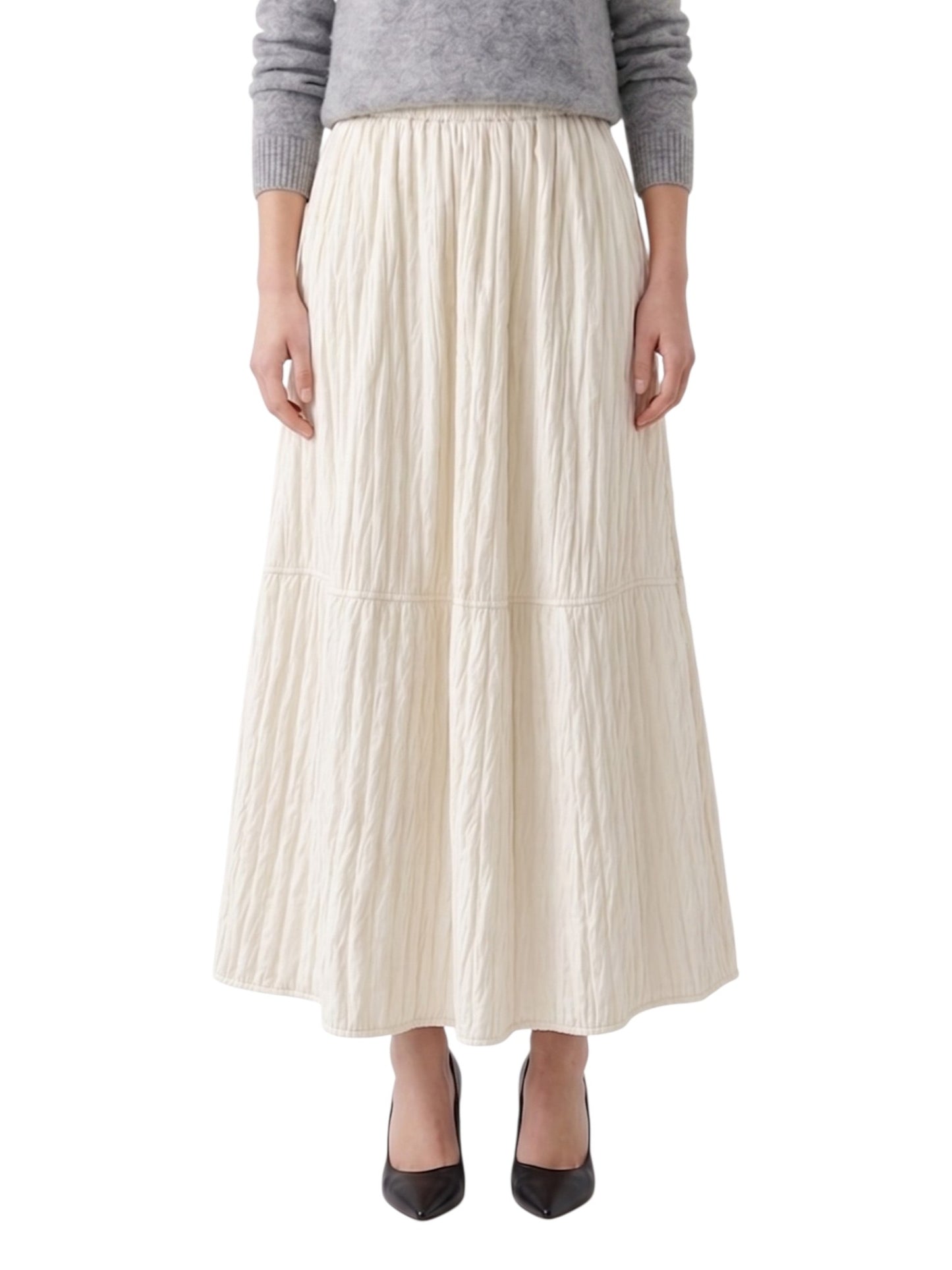 Person wearing a long ivory pleated skirt on a white background