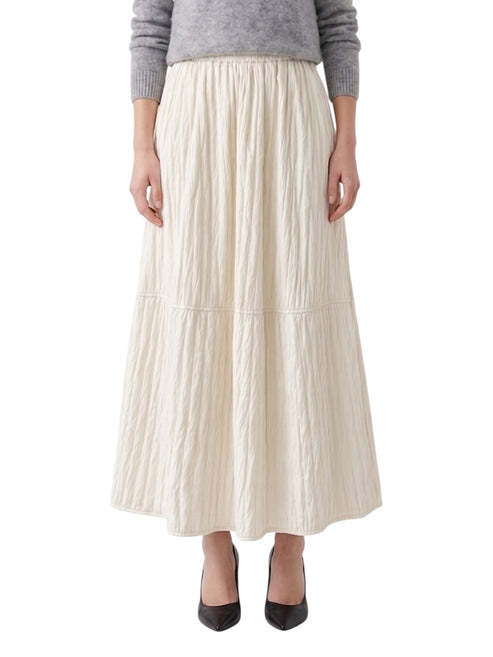 Person wearing a long ivory pleated skirt on a white background