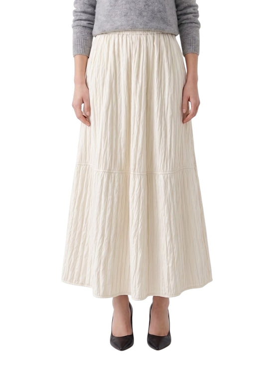 Person wearing a long ivory pleated skirt on a white background
