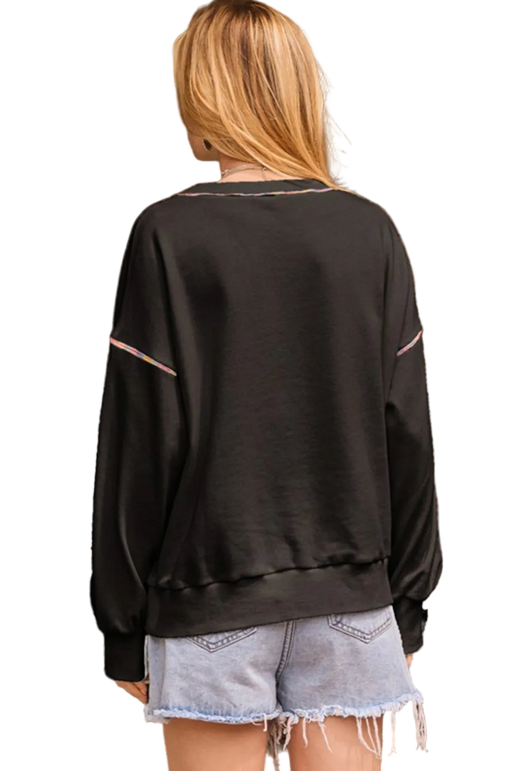 Person wearing a black sweatshirt with pink accents in front of a white background.