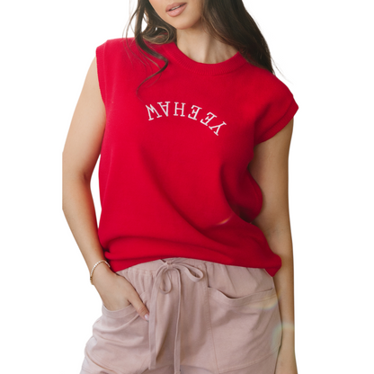 Model wearing a vibrant red sleeveless knit vest with white "YEEHAW" embroidery in a western font across the chest.