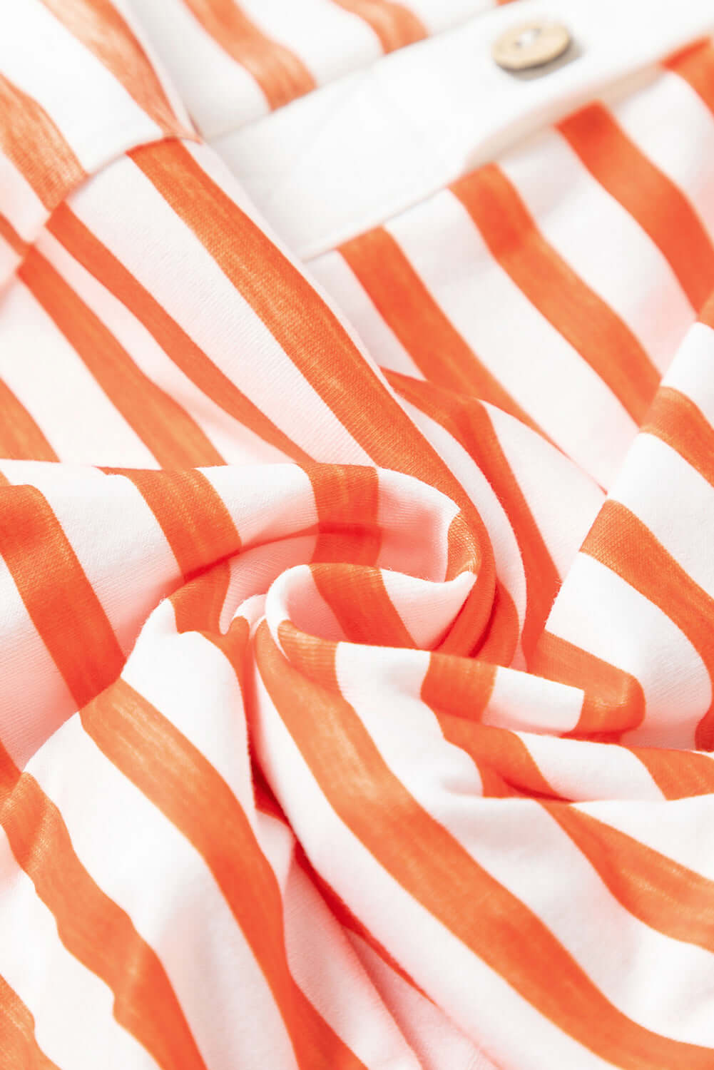 Closed up fabric view of an orange striped wide-leg jumpsuit with pockets.
