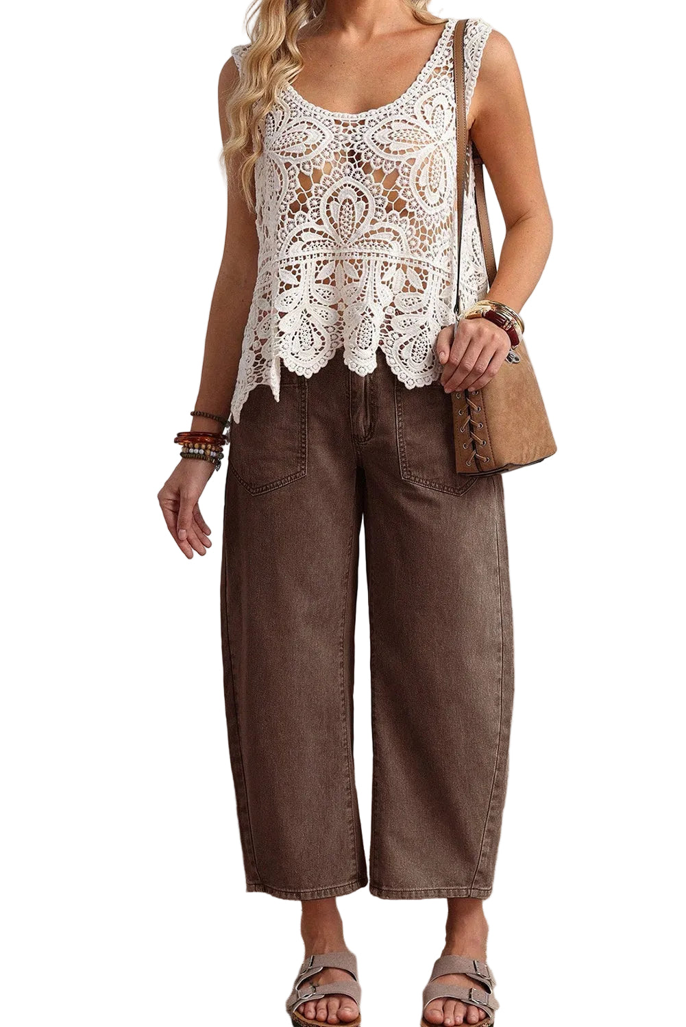 Person wearing a white lace top and brown wide-leg jeans, holding a beige handbag.