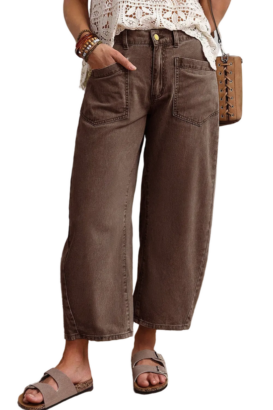 Front view of a model wearing brown cropped barrel leg cotton jeans with utility patch pockets and slides.