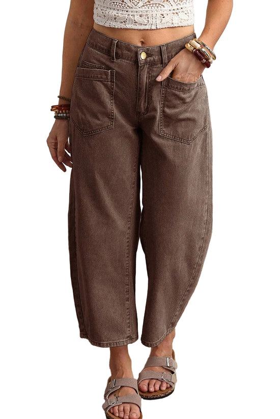 Person wearing brown wide-leg jeans with a white top and sandals on a beige carpet.