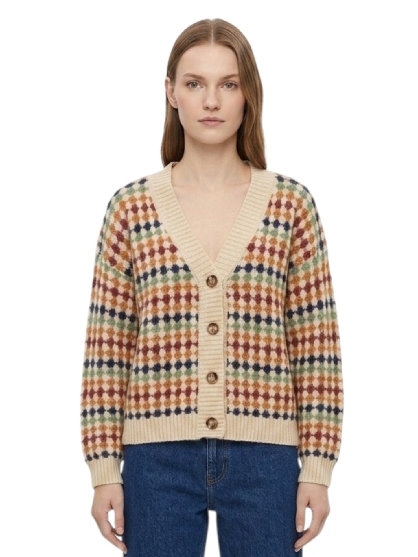 A woman wearing a cream-colored knit cardigan with a multicolor geometric pattern in red, blue, green, and yellow, paired with blue jeans, against a plain white background.