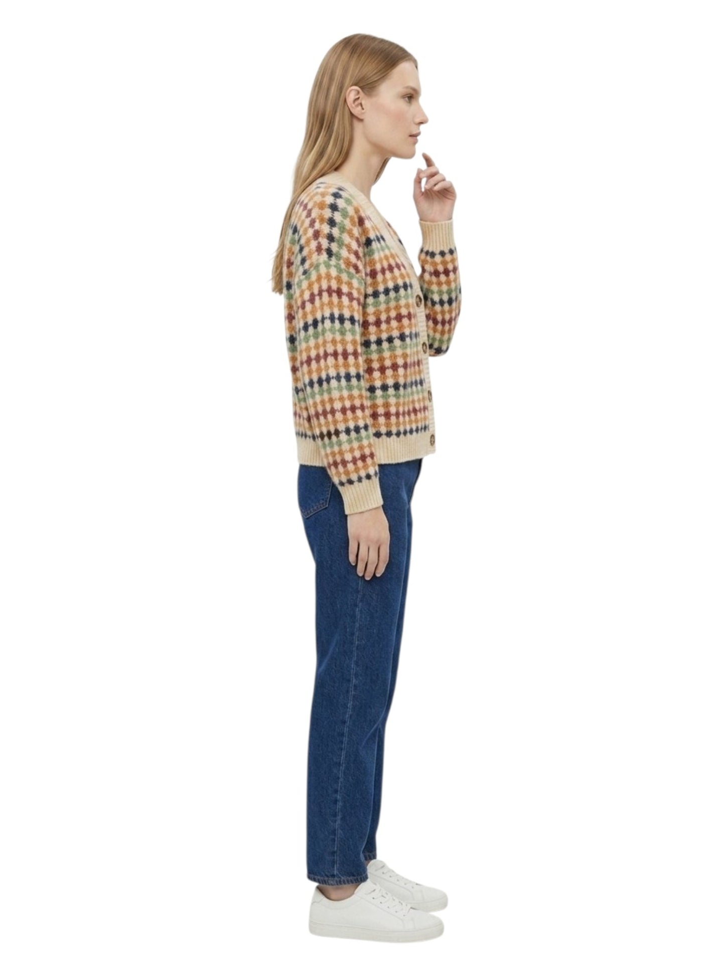 A woman shown in profile wearing a cropped, multicolor plaid knit cardigan with beige ribbed trim, blue jeans, and white sneakers against a plain white background.