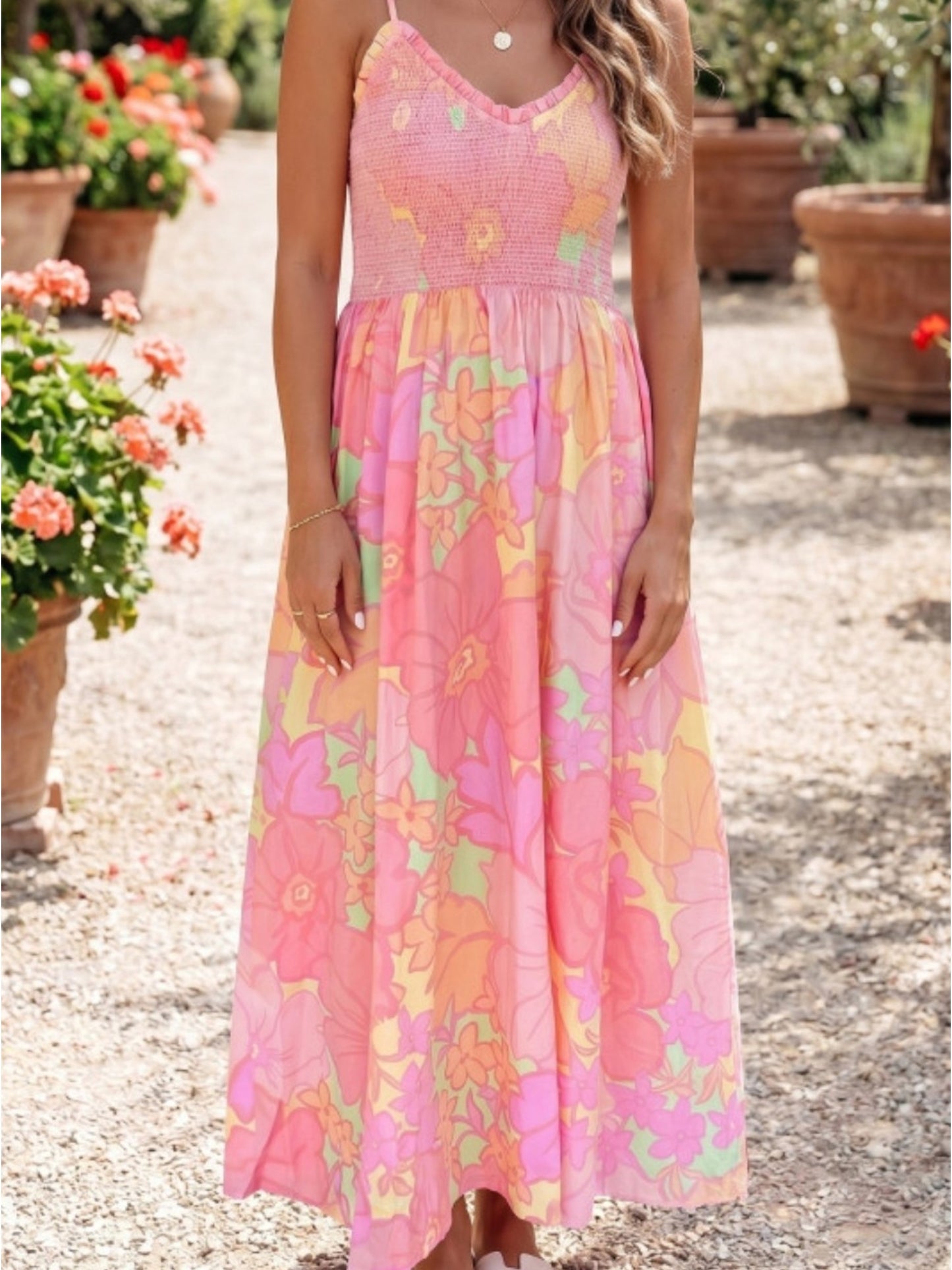 Woman wearing a pink floral dress standing outdoors with plants in the background