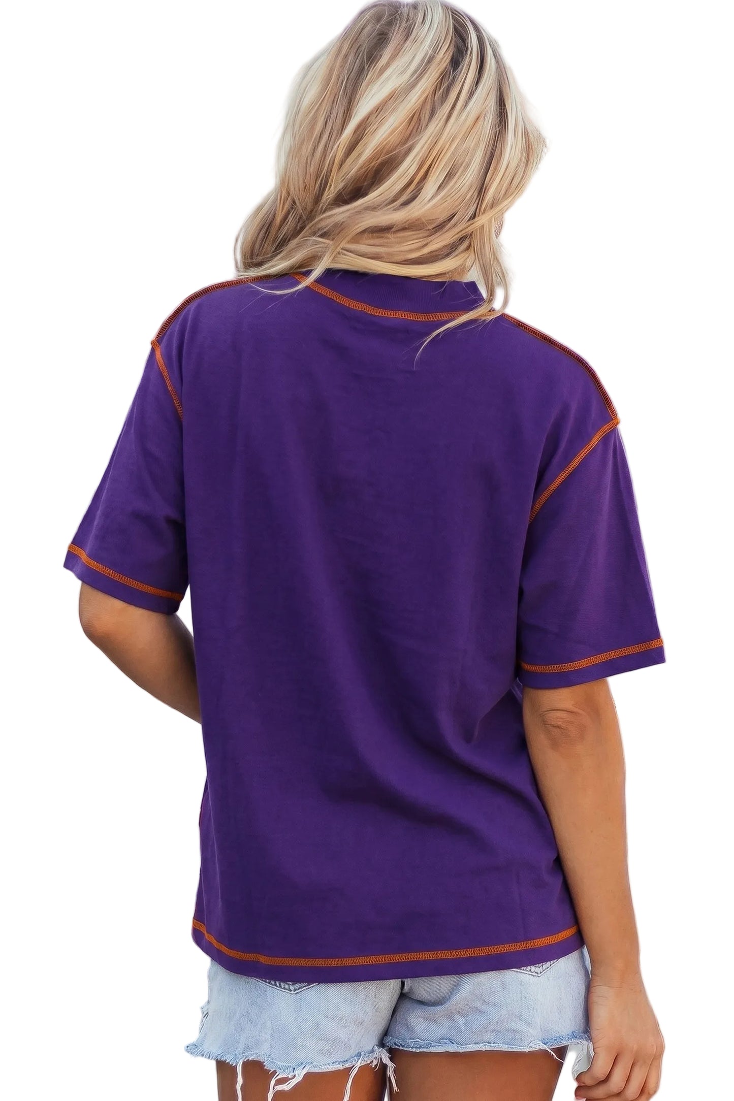 Rear view of a woman wearing a purple mock neck oversized t-shirt featuring bright orange contrast stitching along the seams and dropped shoulders.