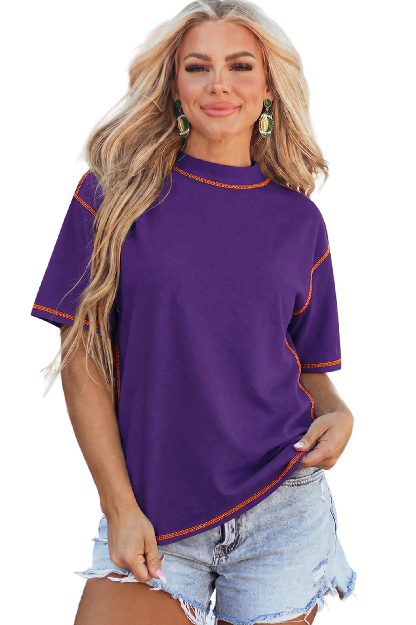 Model wearing a purple mock neck oversized t-shirt featuring bright orange contrast stitching along the seams and dropped shoulders.