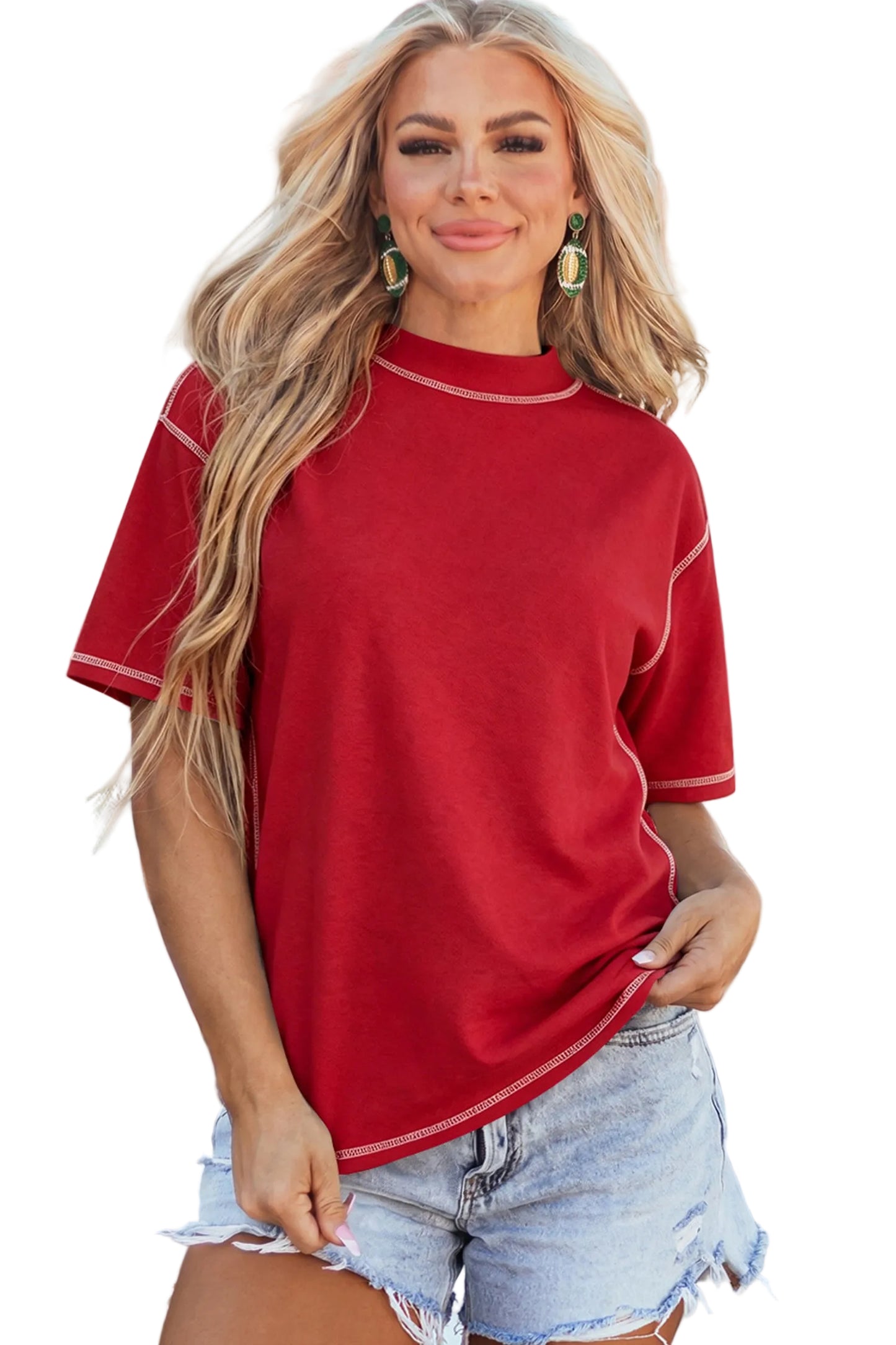 Model wearing a crimson red drop-shoulder basic tee with white structural exposed contrast stitching paired with light denim shorts.
