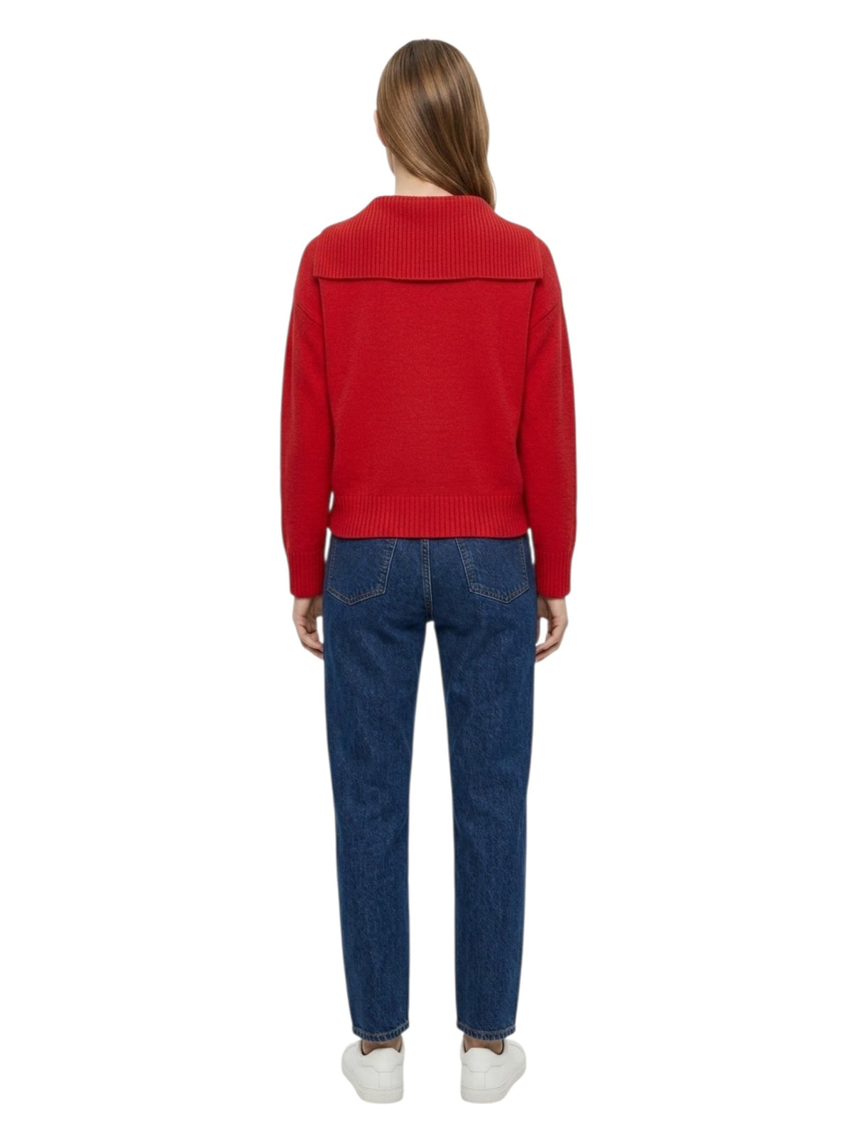 A woman viewed from the back wearing a bright red knit sweater with a wide shoulder yoke, blue jeans, and white sneakers, set against a plain white background.