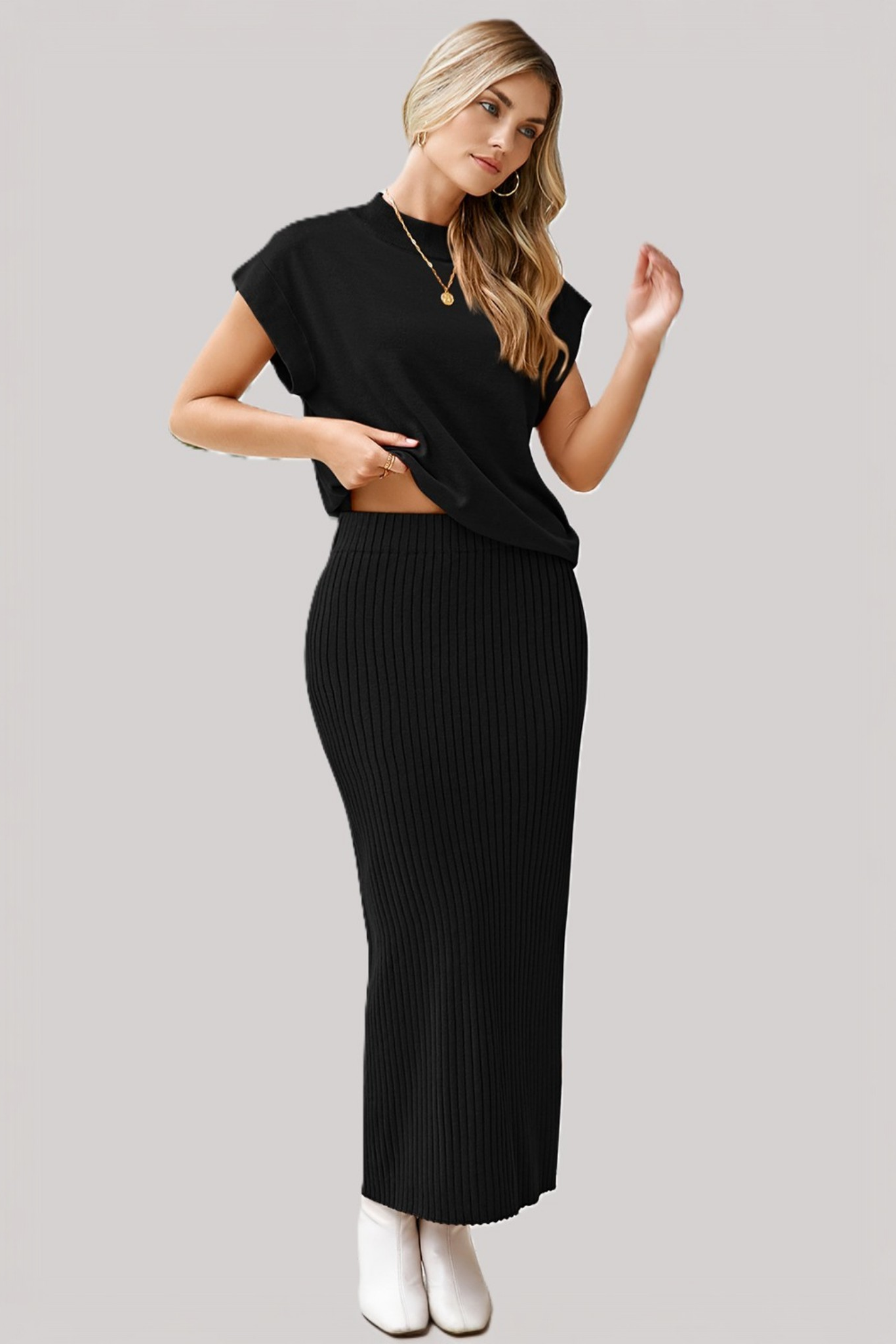 A model wearing a solid black two-piece set featuring a relaxed-fit dolman-sleeve tee and a matching ribbed midi skirt with a side slit, showcase the skirt's elastic waistband.