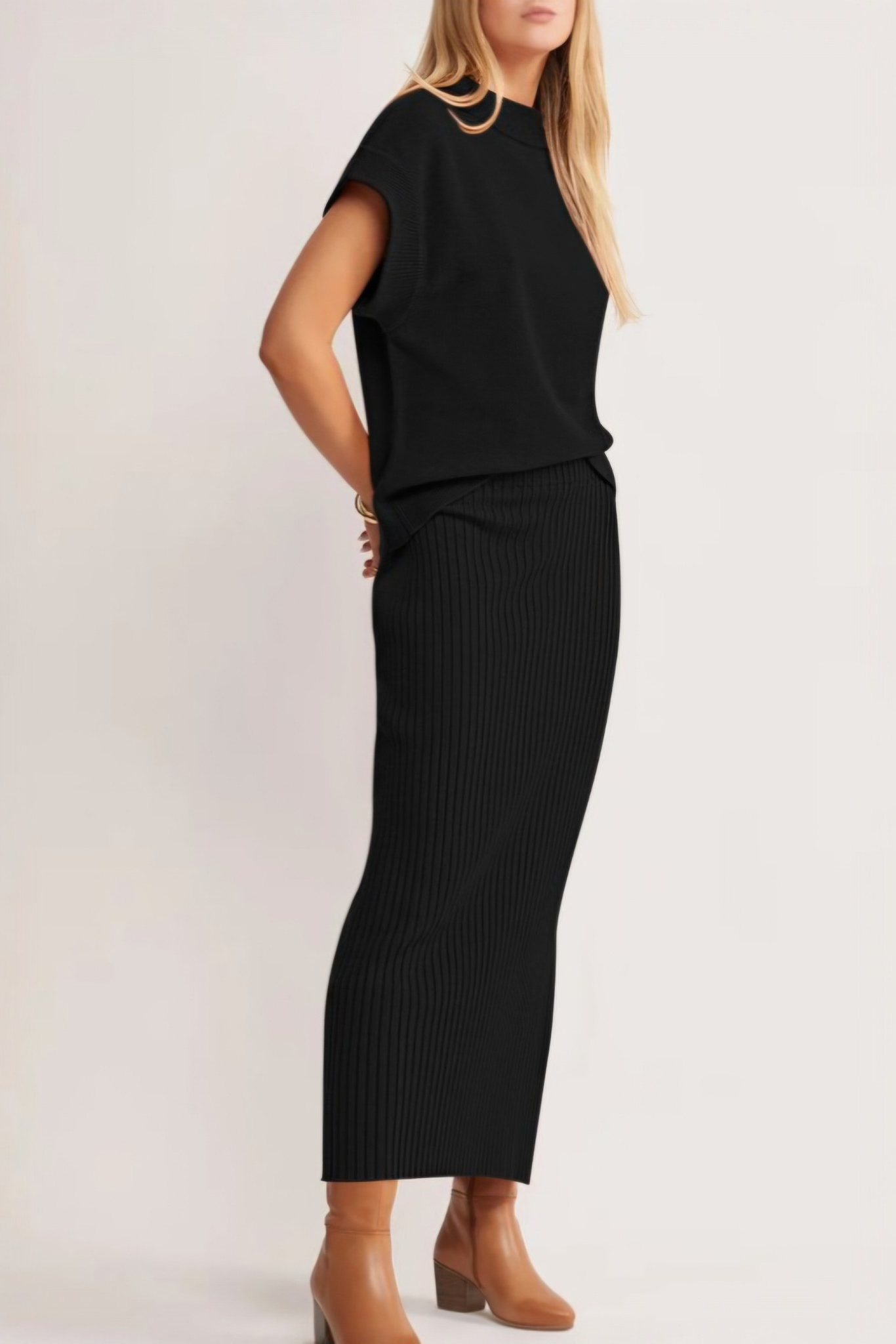 Side view of a model wearing a solid black two-piece set featuring a relaxed-fit dolman-sleeve tee and a matching ribbed midi skirt with a side slit.
