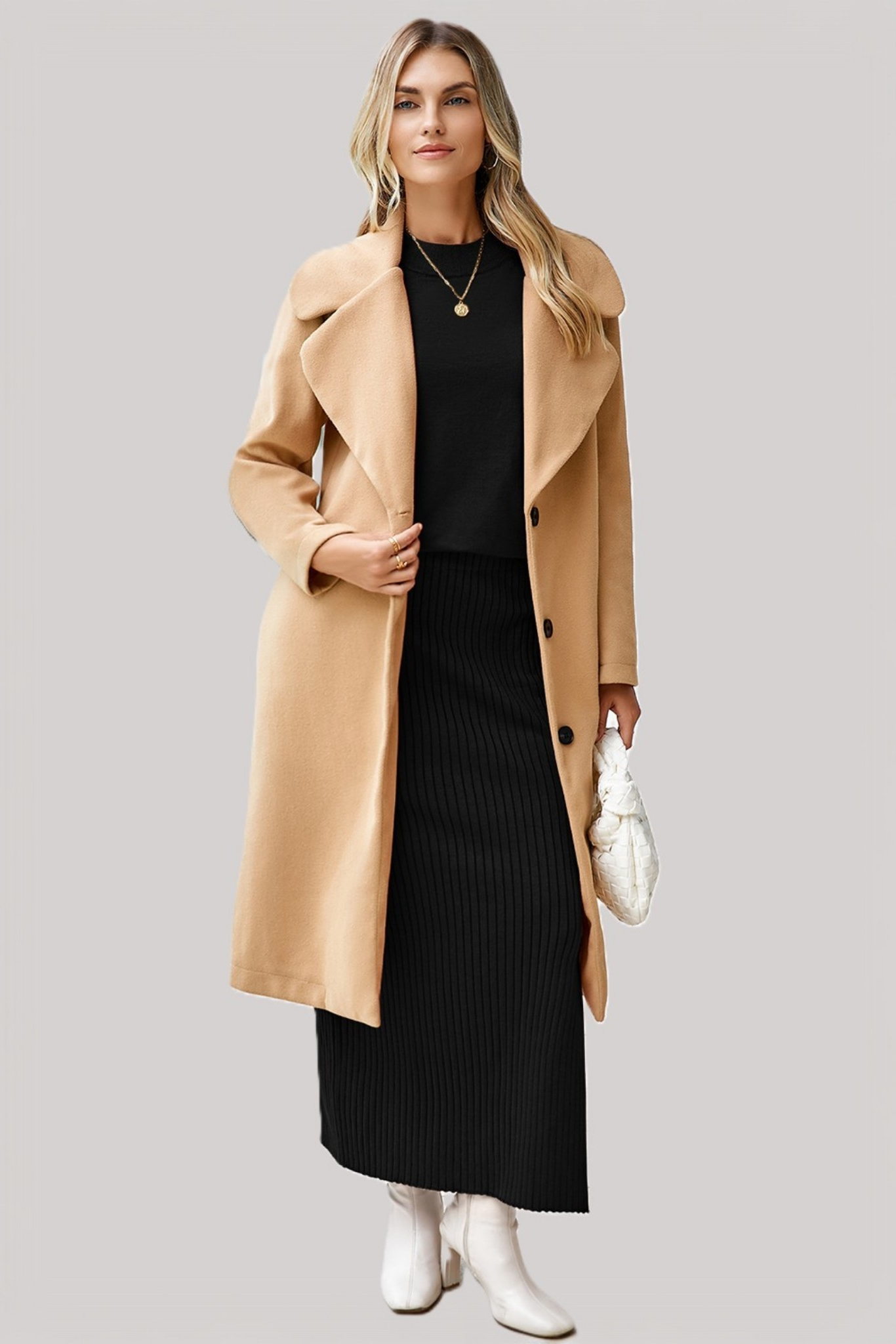 A model wearing a solid black two-piece set featuring a relaxed-fit dolman-sleeve tee and a matching ribbed midi skirt with a side slit, styling with a beige neutral winter coat.