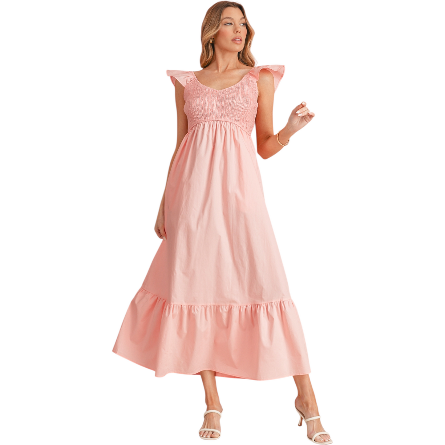 Model wearing a flowy peach cotton summer dress with ruffle sleeves and a smocked bodice, styled with white strappy heels.