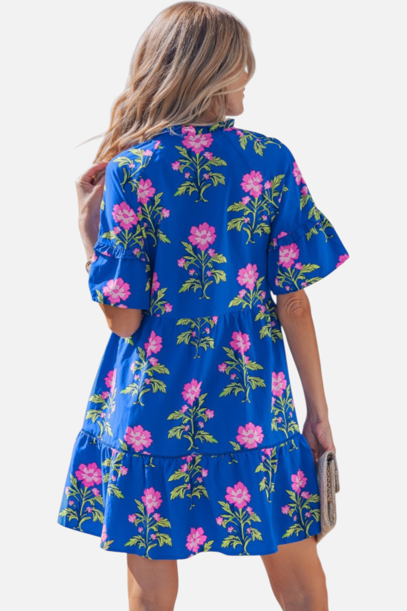 Rear view of a model in a vibrant cobalt blue floral mini dress, highlighting the relaxed shift silhouette and tiered ruffle hemline.