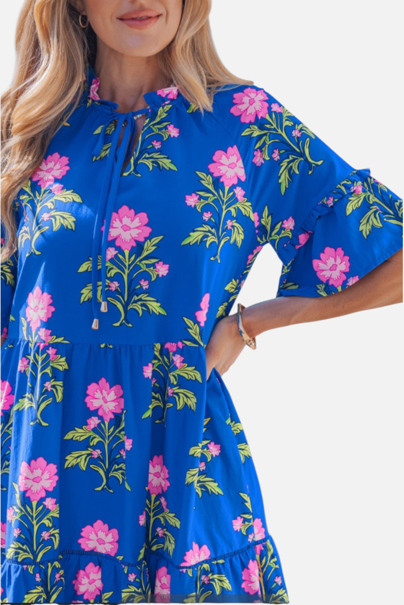 Close-up detail of the floral mini dress featuring a gathered tie-neckline and layered ruffle sleeves in a pink and blue botanical print.