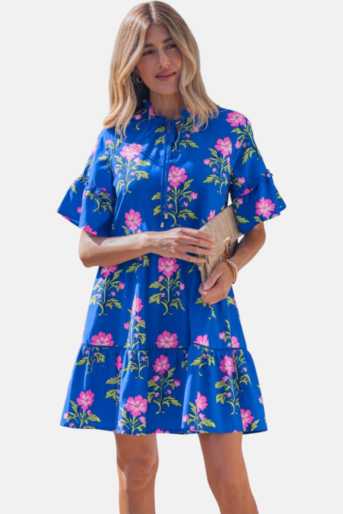 Studio-style front shot of the tiered floral mini dress, highlighting the flattering V-neck opening and relaxed-fit ruffled sleeves.