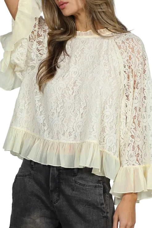 Woman wearing a white lace blouse with ruffled sleeves and hem.