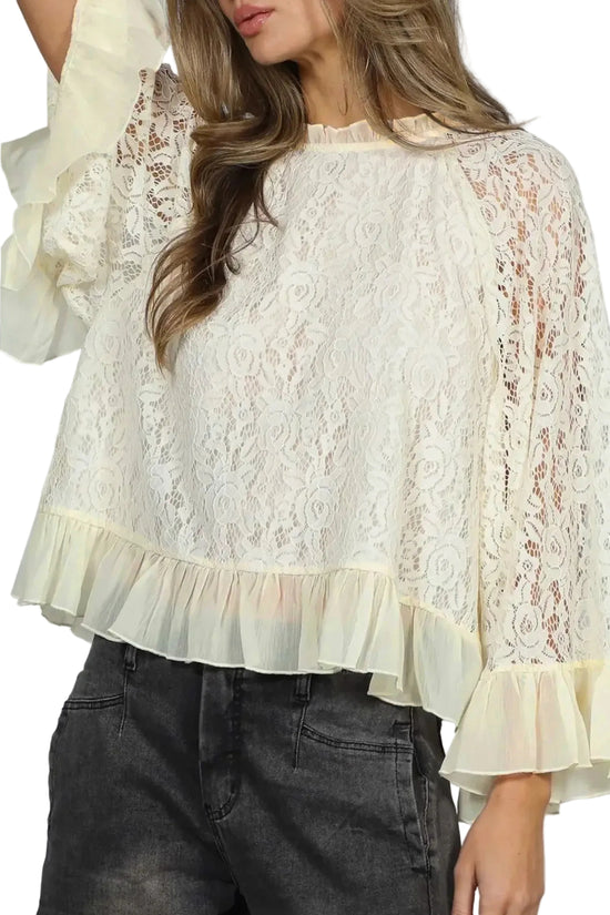 Woman wearing a white lace blouse with ruffled sleeves and hem.
