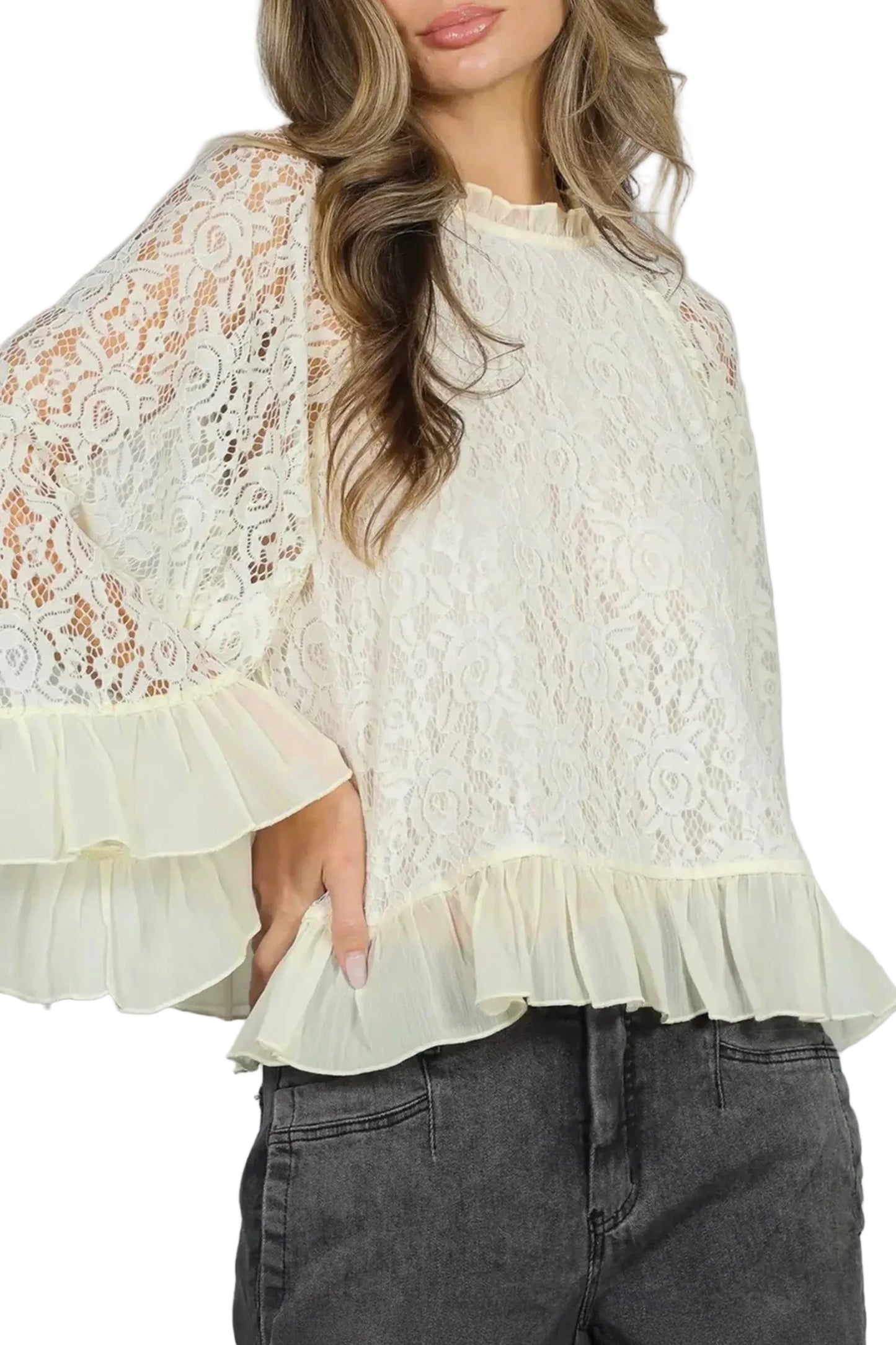 Woman wearing a white lace blouse with ruffled sleeves and hem against a plain background
