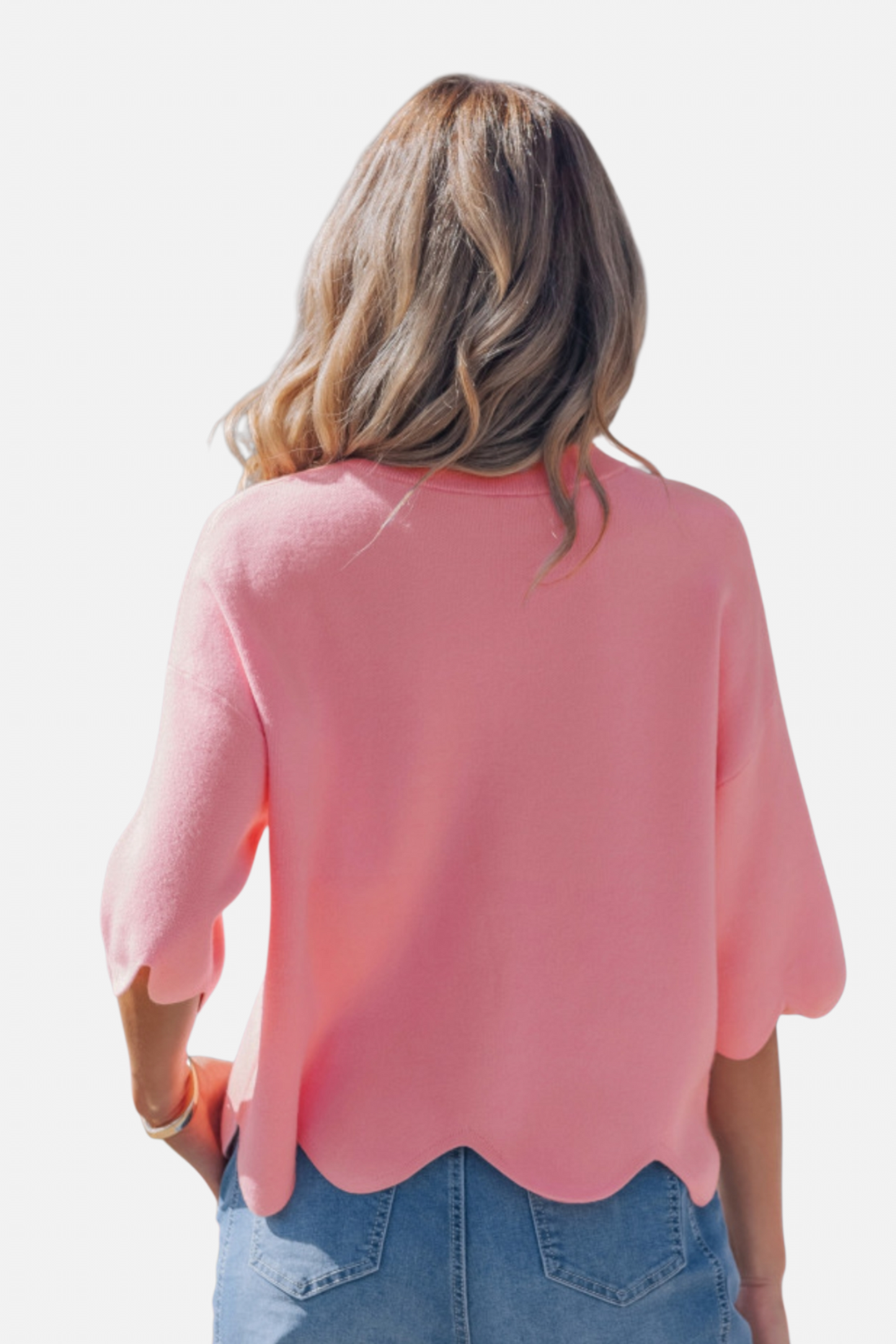 Woman wearing a pink blouse with scalloped hem on a white background