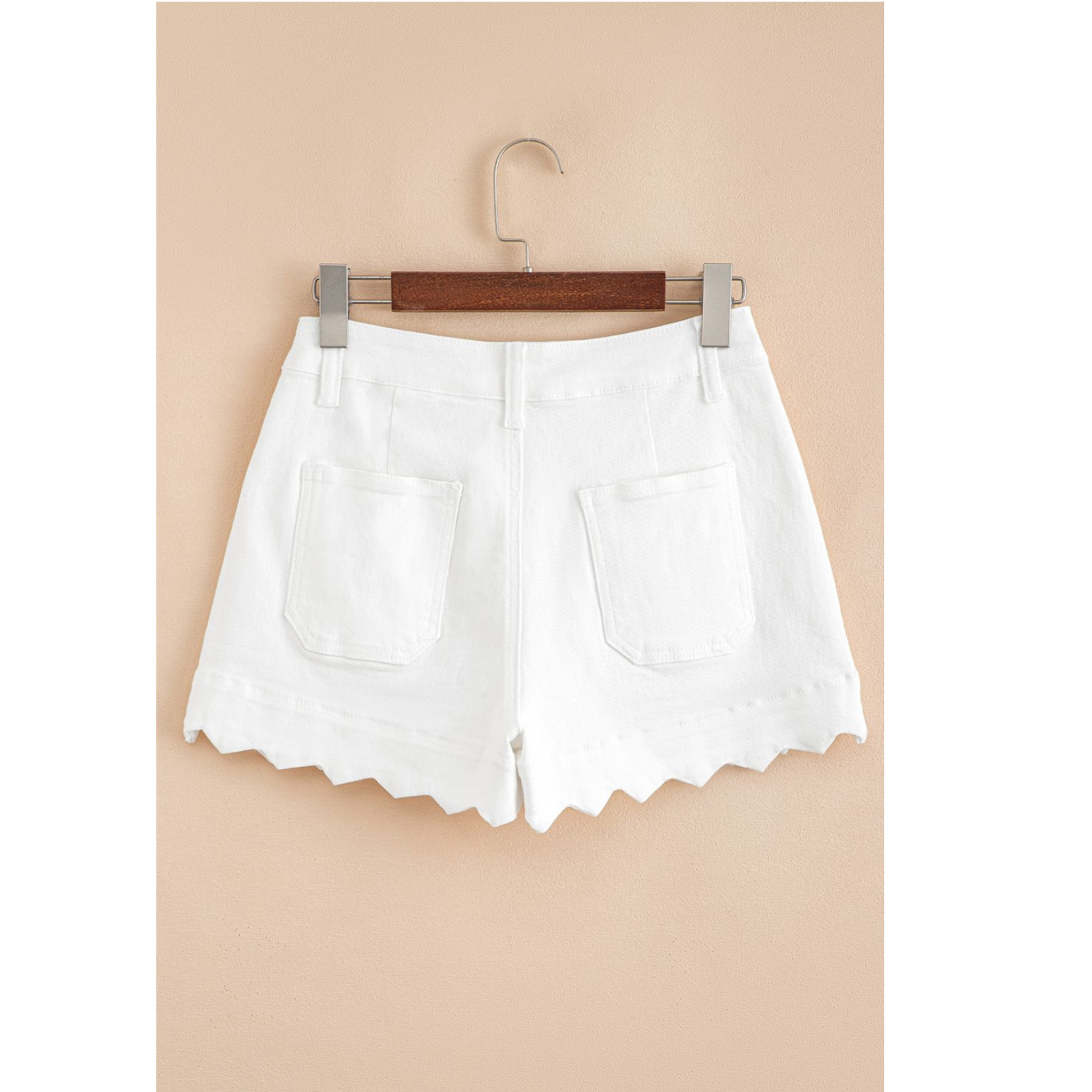 White shorts on a hanger against a beige background
