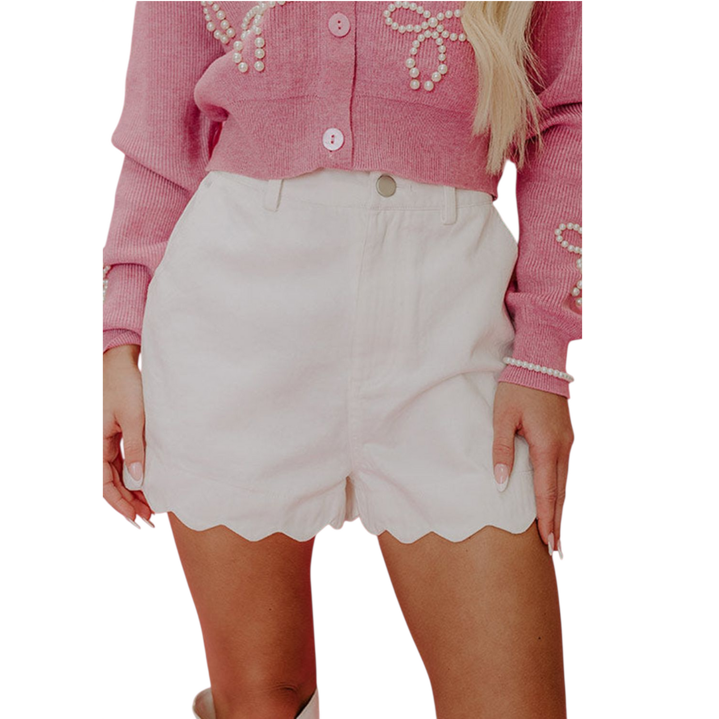 Person wearing a pink blouse with pearl embellishments and white shorts on a white background