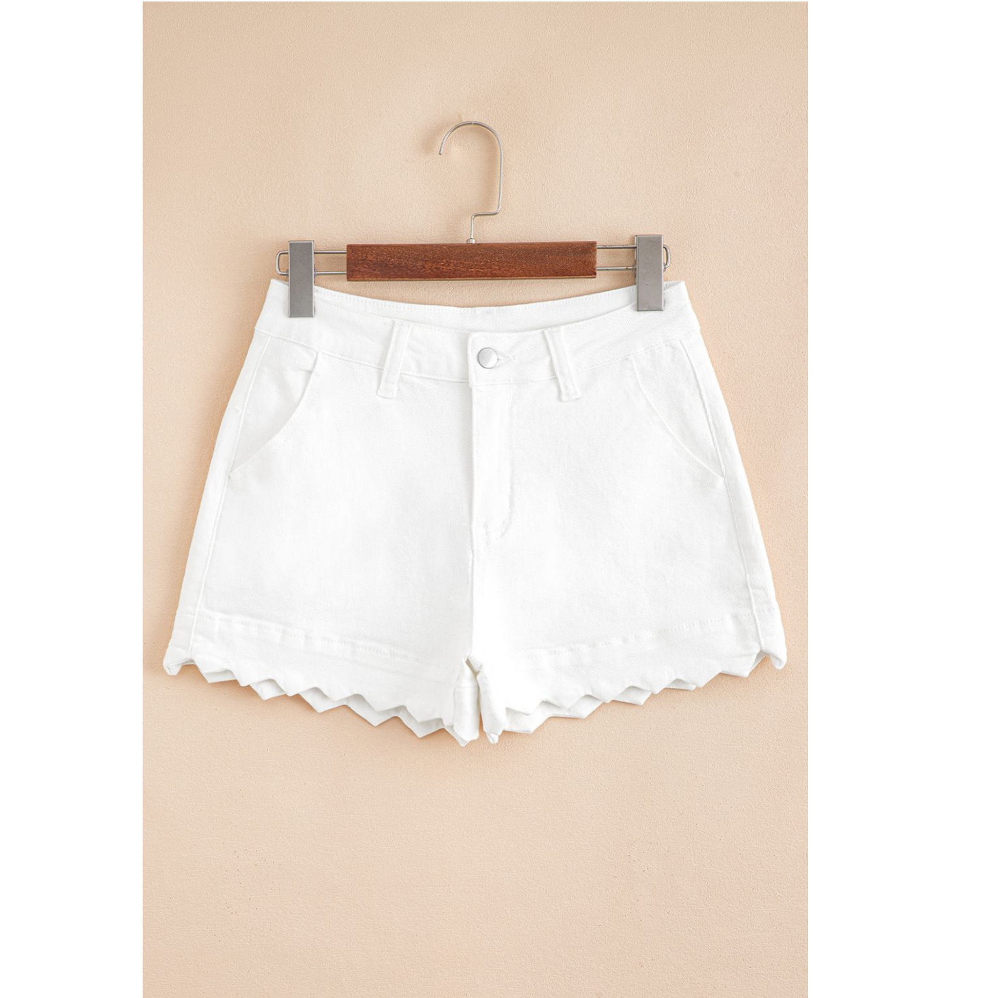 White shorts on a hanger against a beige background