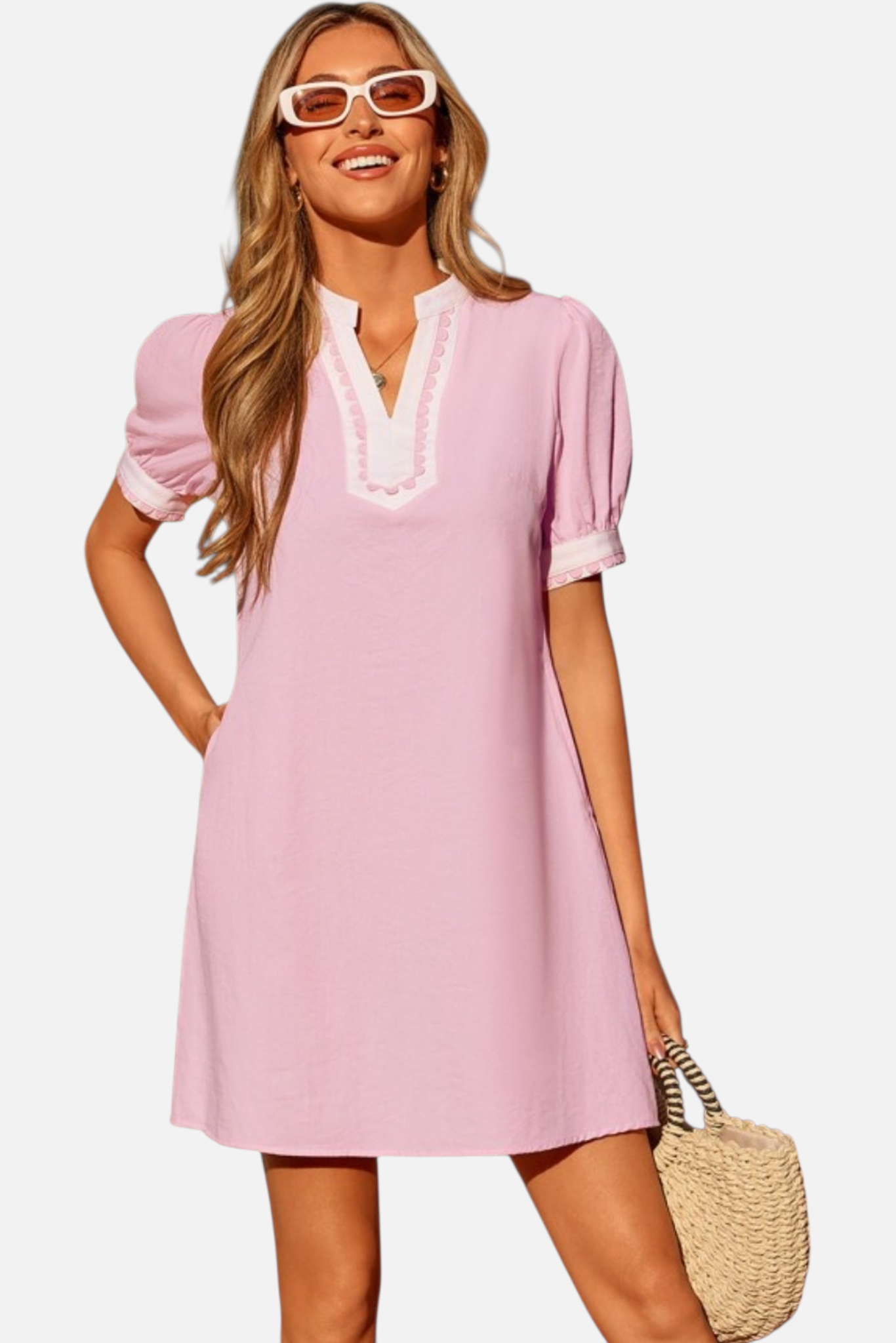 Woman wearing a pink dress with white trim on a plain background