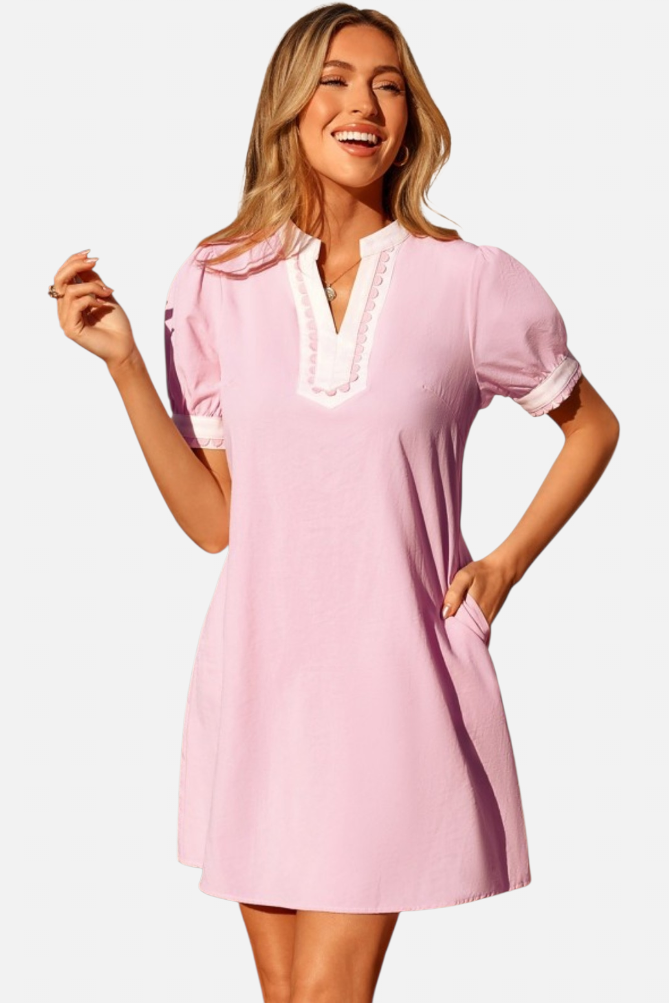 Woman wearing a pink dress with white trim on a plain background