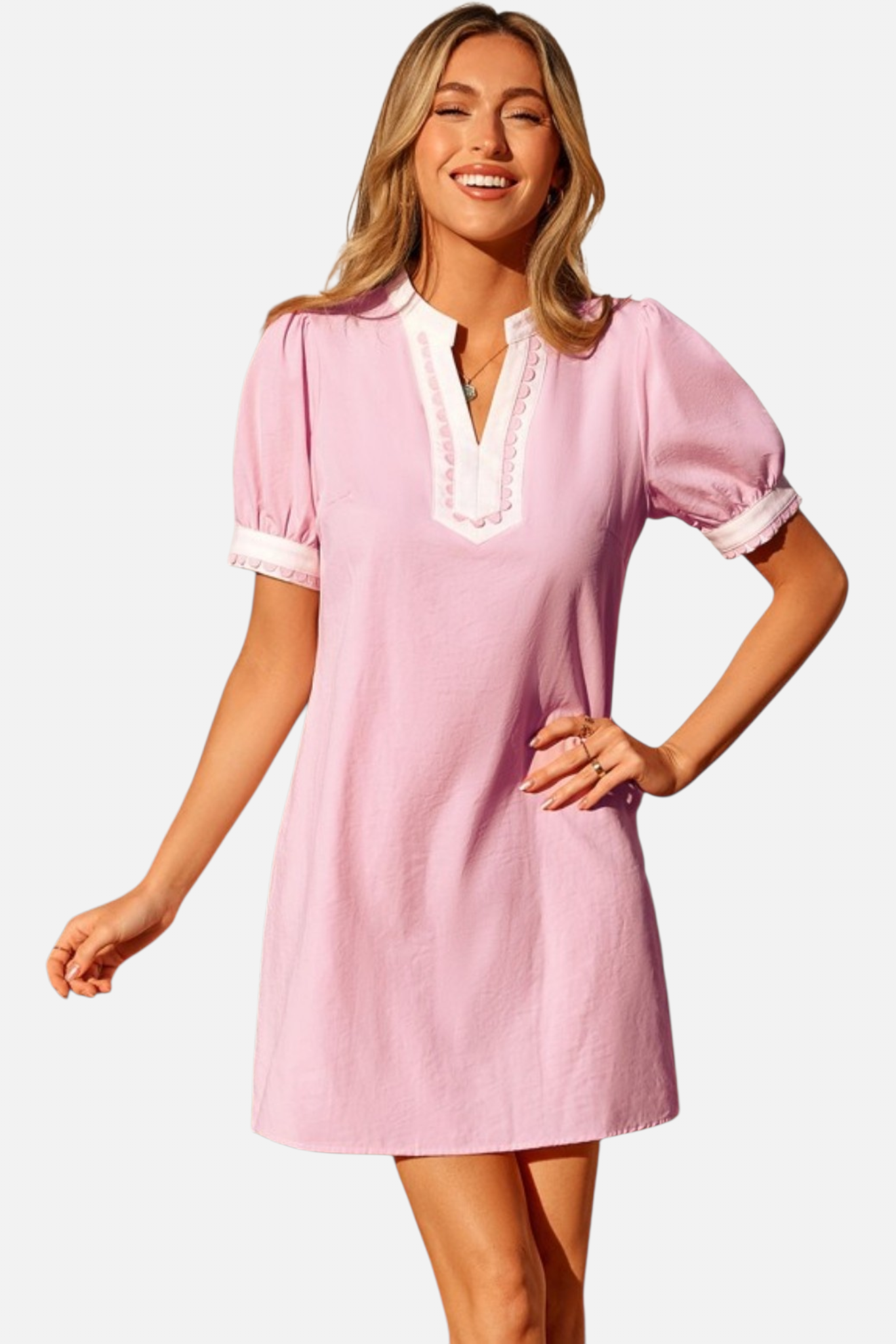Woman wearing a pink dress with white trim on a plain background