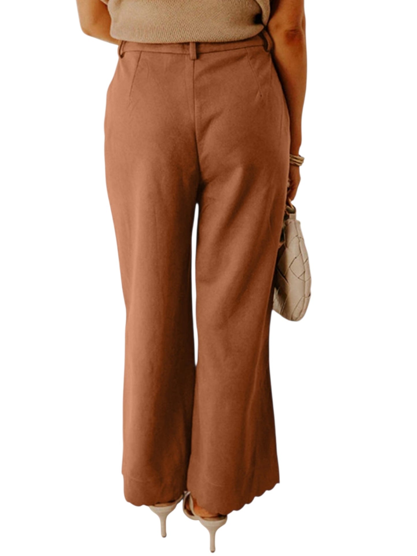 A person shown from the waist down wearing high-waisted, wide-leg brown pants, paired with a beige top, beige heels, and holding a beige quilted handbag against a plain white background.