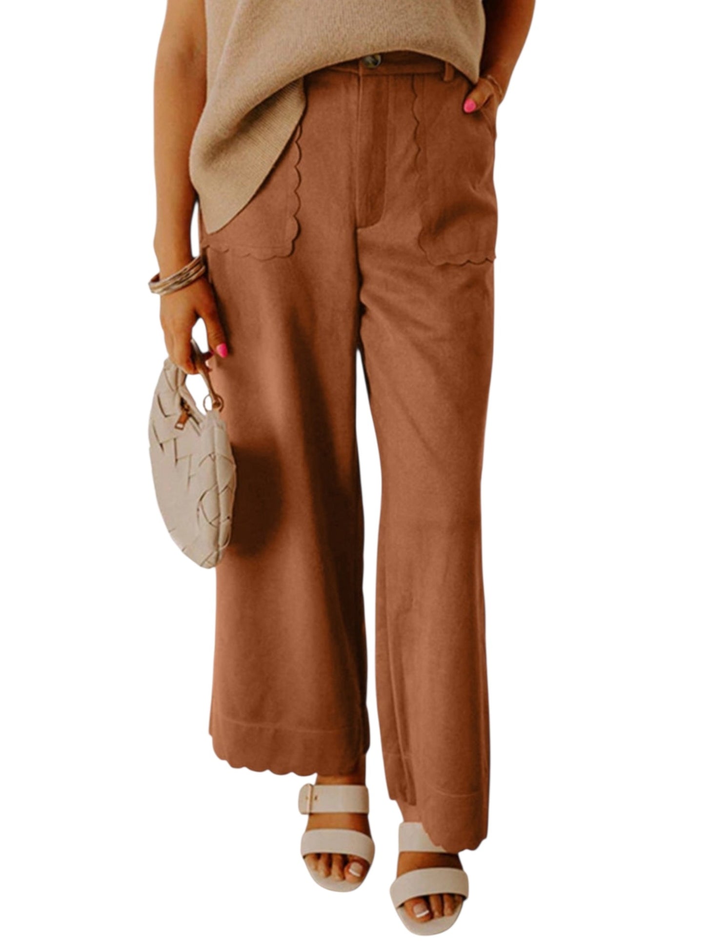 A person wearing wide-leg brown pants with scalloped hems, paired with a beige top and holding a small beige handbag against a plain white background.