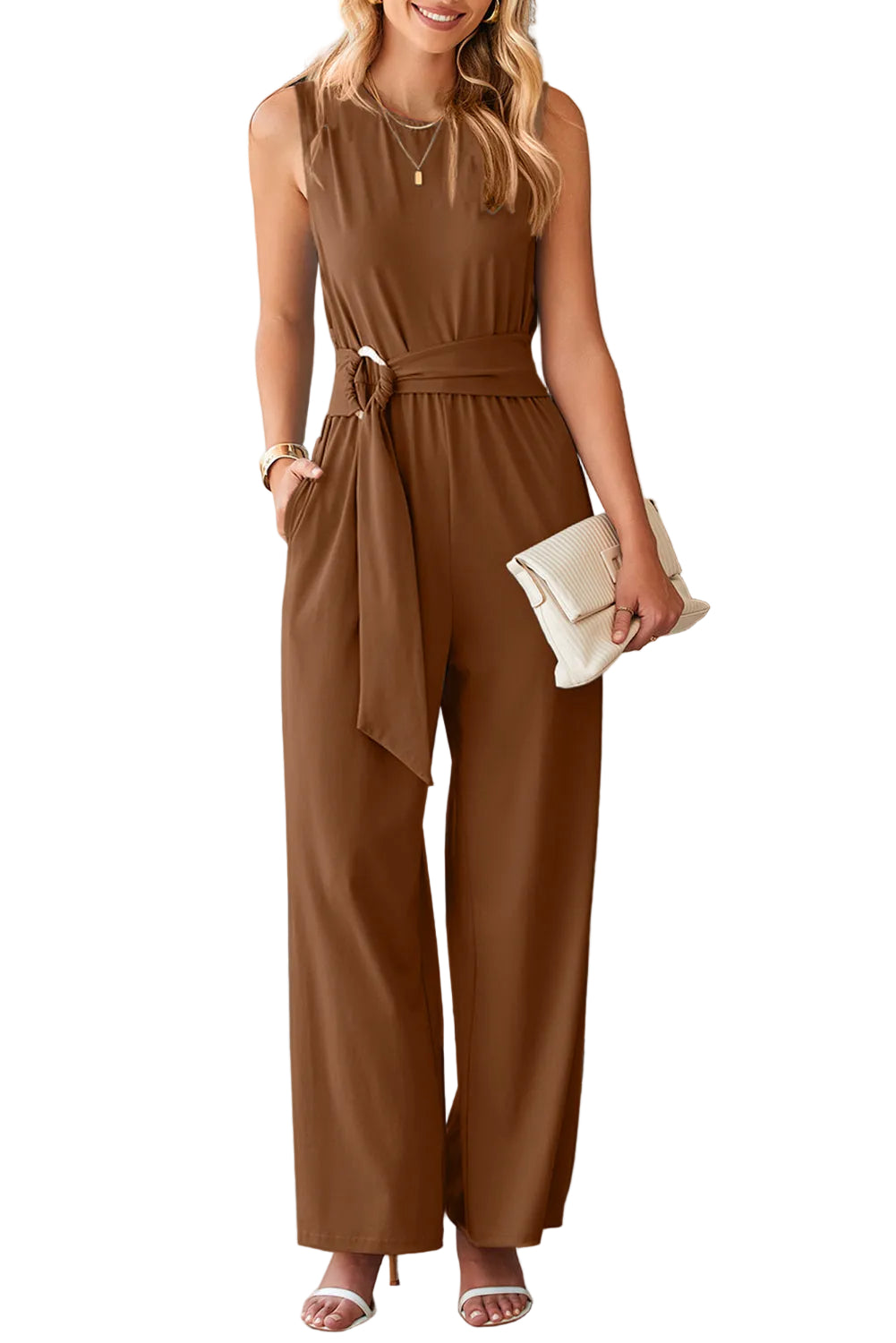 Woman wearing a brown jumpsuit holding a clutch in a white background