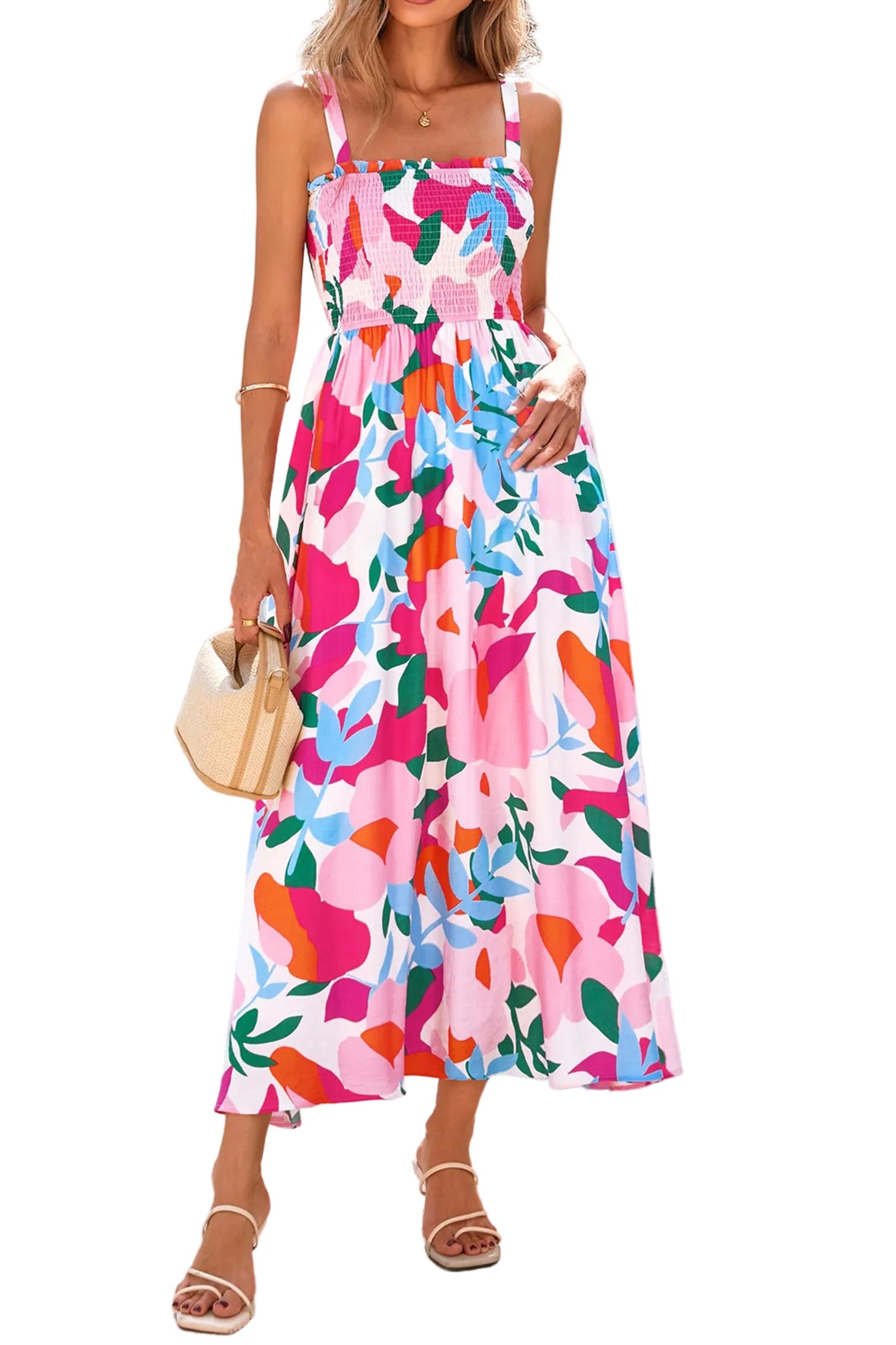 Front full-length view of a model wearing a pink smocked floral high-waisted maxi dress holding a straw bag.