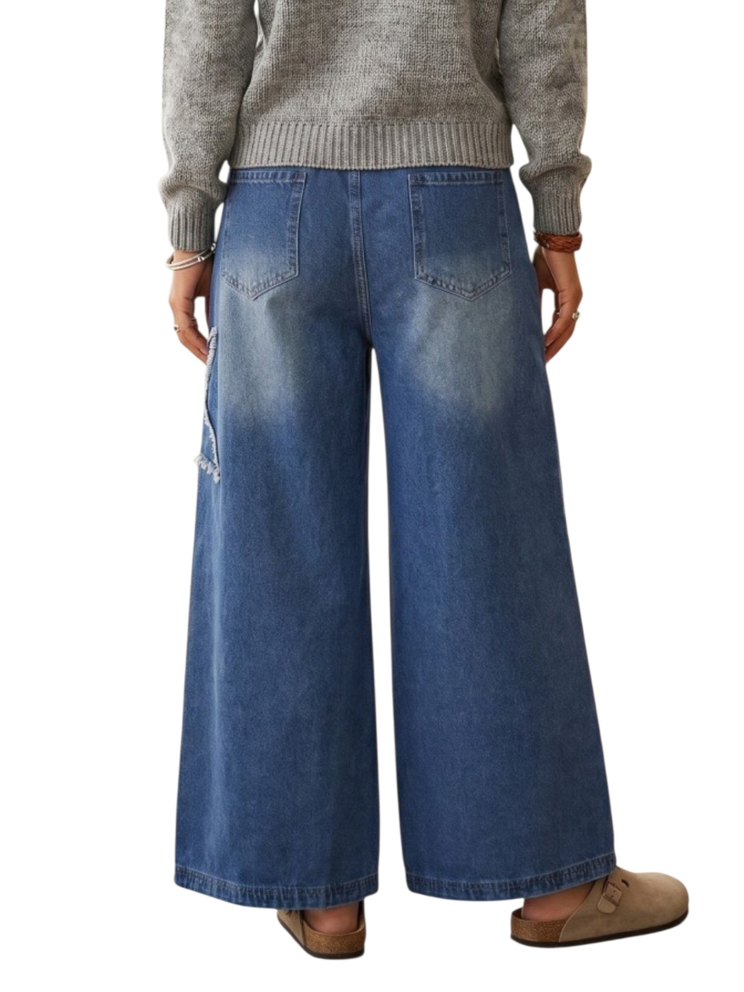 A person shown from the back wearing wide-leg blue denim jeans with a faded wash, a gray ribbed sweater, and tan slip-on shoes against a plain white background.