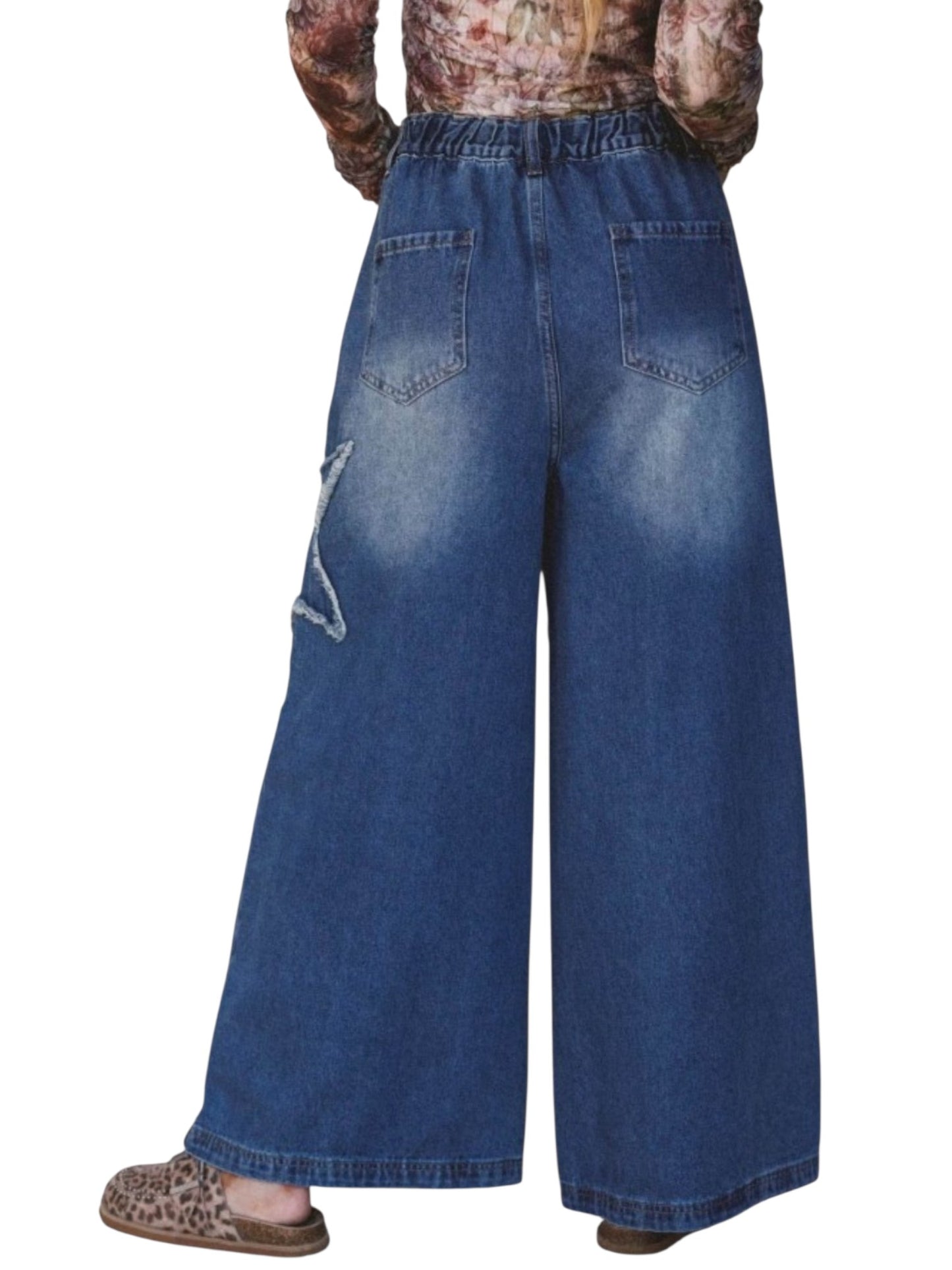 Wide-leg blue denim pants with a faded wash, elastic waistband, and a distressed star detail on the left leg, shown on a model from the back against a white background.