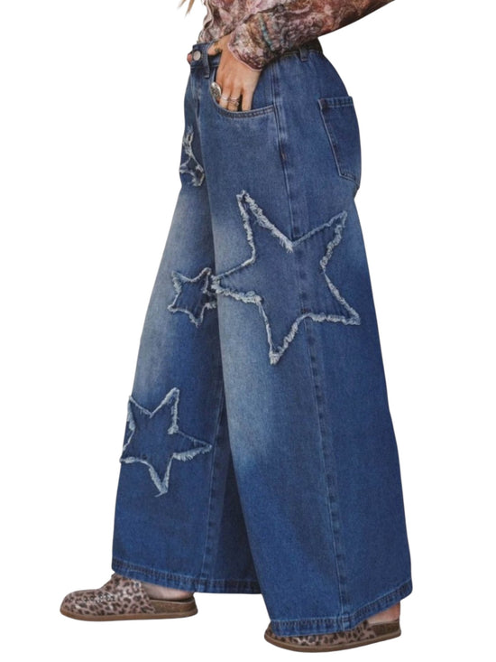 Wide-leg blue denim jeans with large distressed star appliques on the front, shown on a model from the waist down against a white background.
