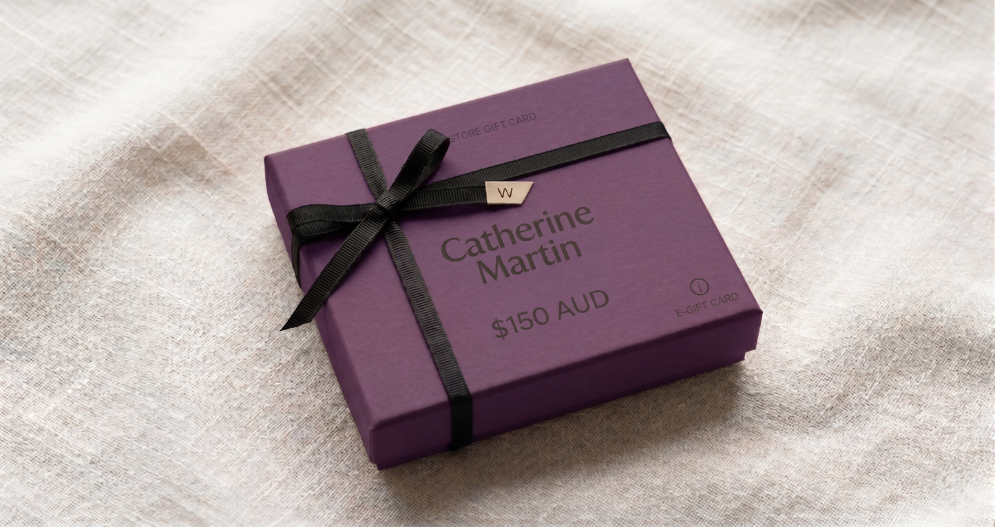 Purple gift box with black ribbon and 'Catherine Martin' branding on a textured surface