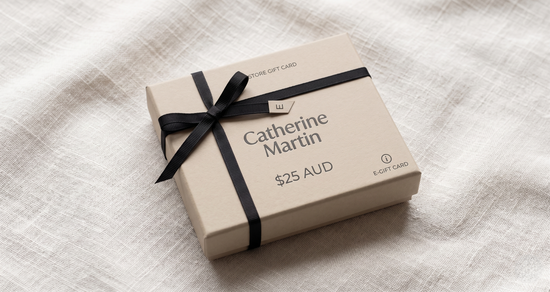 Catherine Martin gift card in a box with a black ribbon on a textured white surface