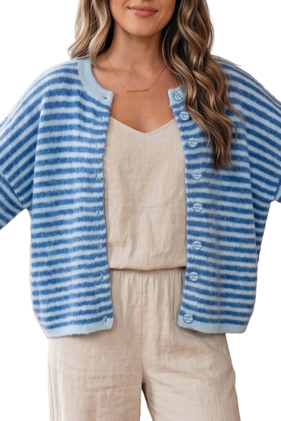Woman wearing a blue and white striped cardigan over a beige top and pants.