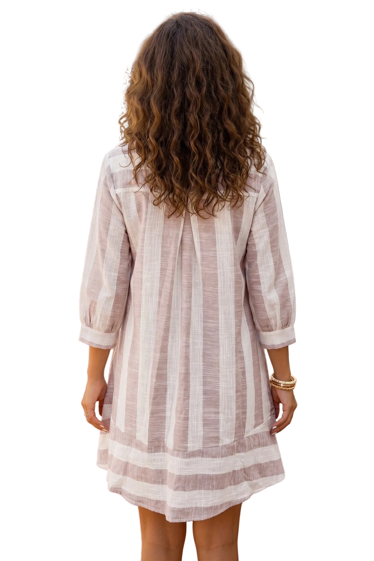 A woman viewed from behind wearing a light pink and white vertically striped linen tunic dress with three-quarter sleeves, set against a white background
