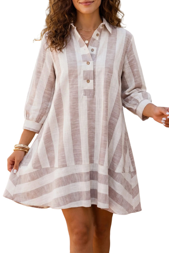 A woman wearing a loose, long-sleeve striped shirt dress in beige and white, standing in against a white background