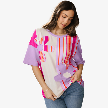 Woman wearing a colorful striped shirt with floral designs on a white background