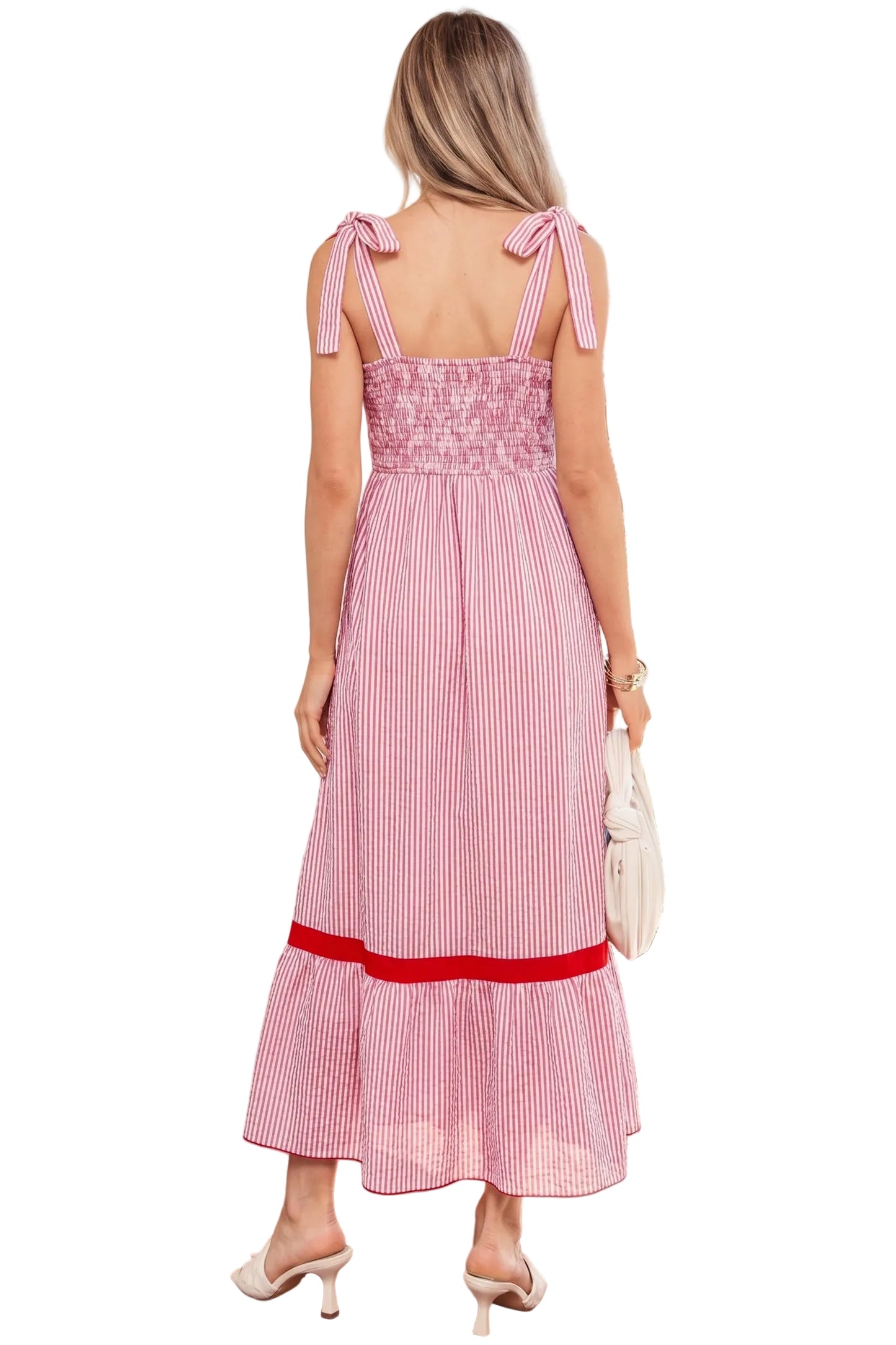 Woman wearing a pink and white striped dress with bow straps on a white background