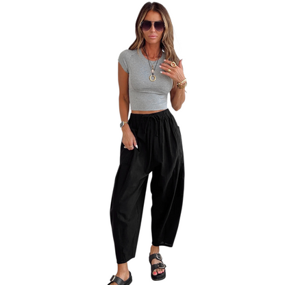 Woman wearing a gray crop top and black high-waisted pants on a white background