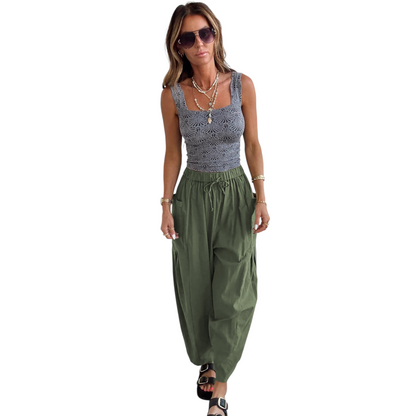 Woman wearing a gray sleeveless top and green wide-leg pants on a white background